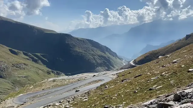 Winding road up to Rohtang Pass through green hills in summer