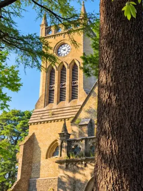 Clock tower of Christ Church in Kasauli framed by tall trees