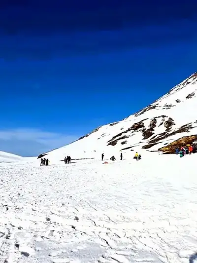 Visitors walking up a snow slope at Kufri near Shimla