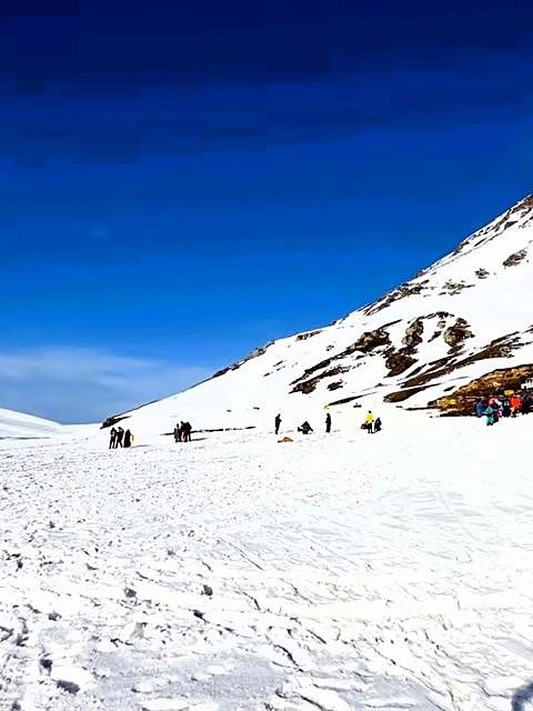Visitors walking up a snow slope at Kufri near Shimla