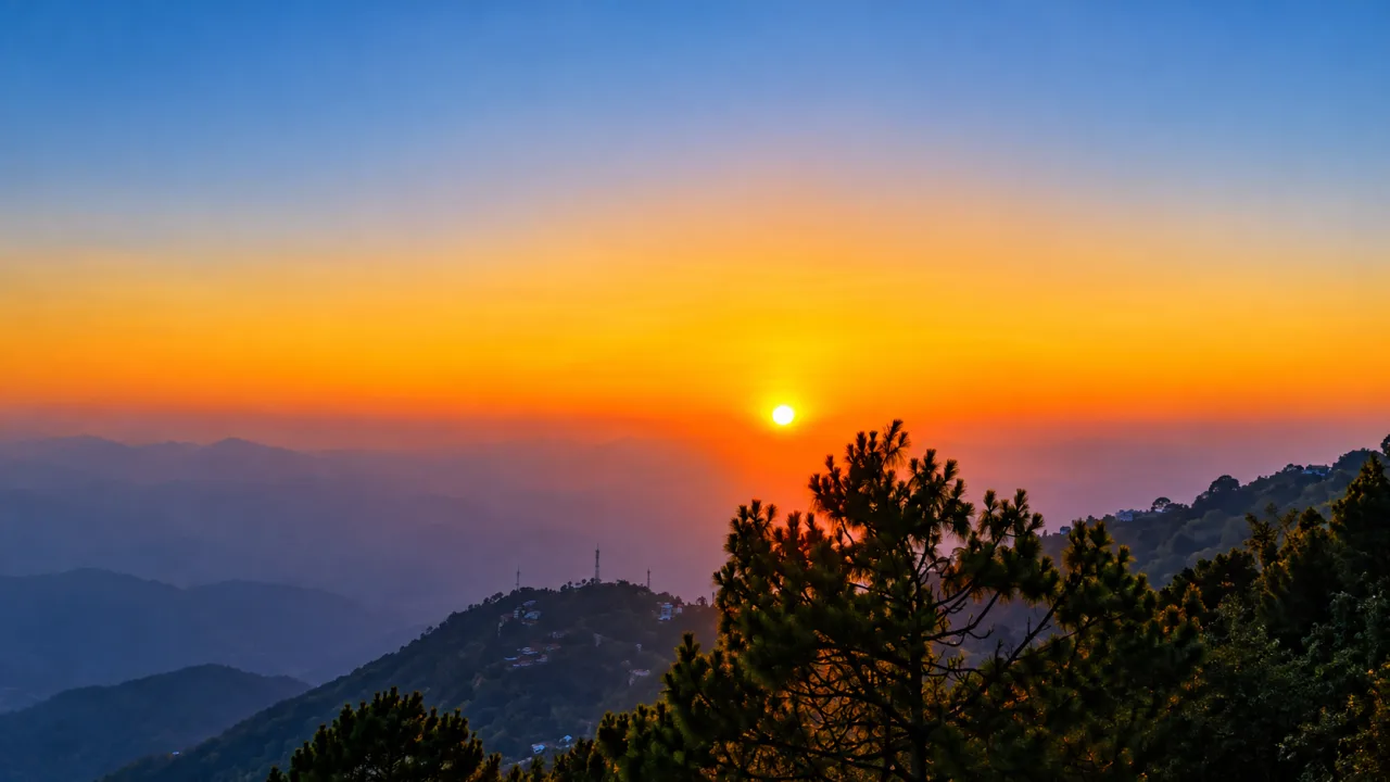Orange sunset over pine-covered hills at Sunset Point, Kasauli