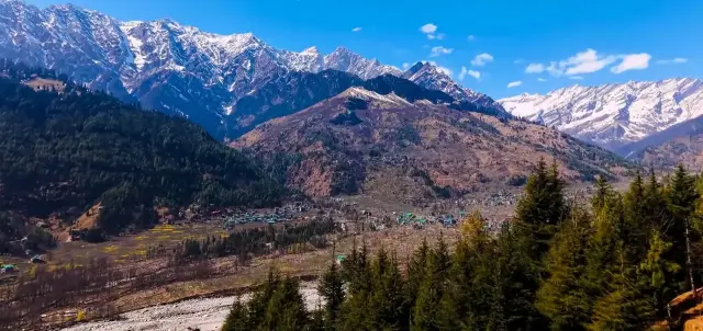 Green valley with snowy mountains above a hill town