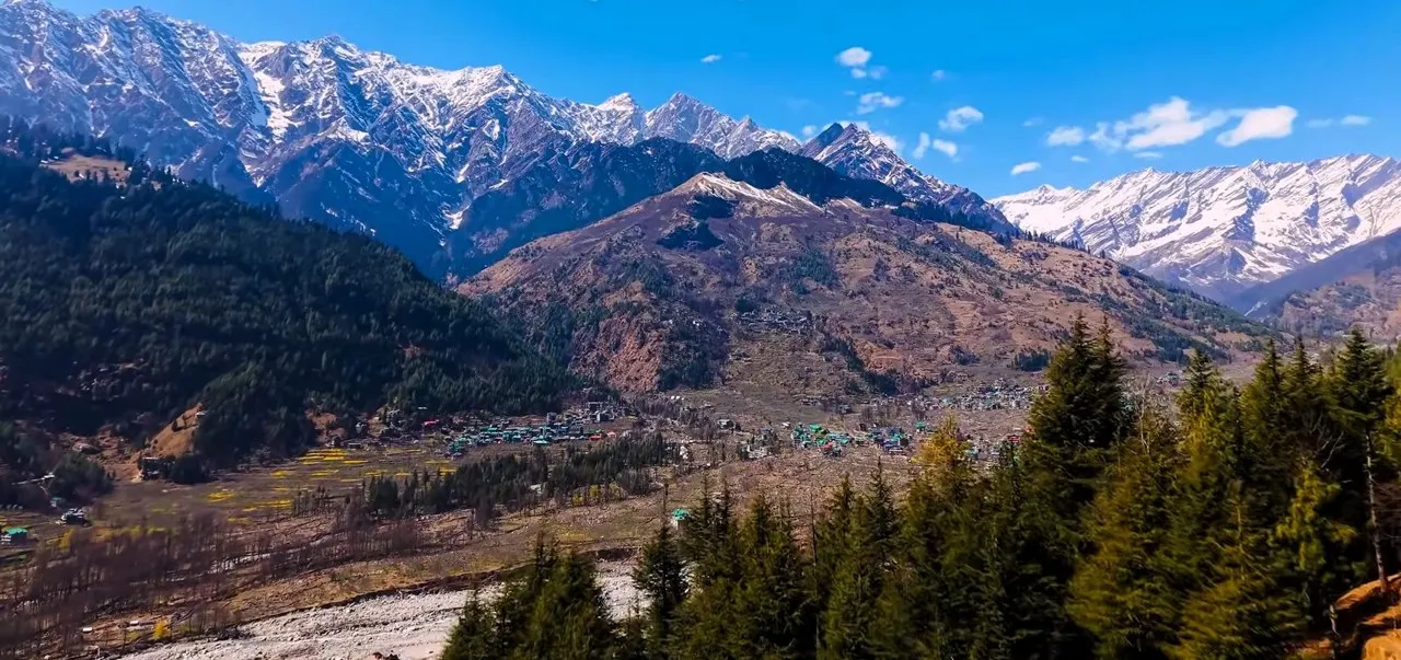 Snow-capped mountain range above a forested valley in Himachal Pradesh