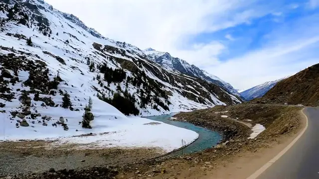 Road beside a river through snow-covered mountains in Himachal Pradesh