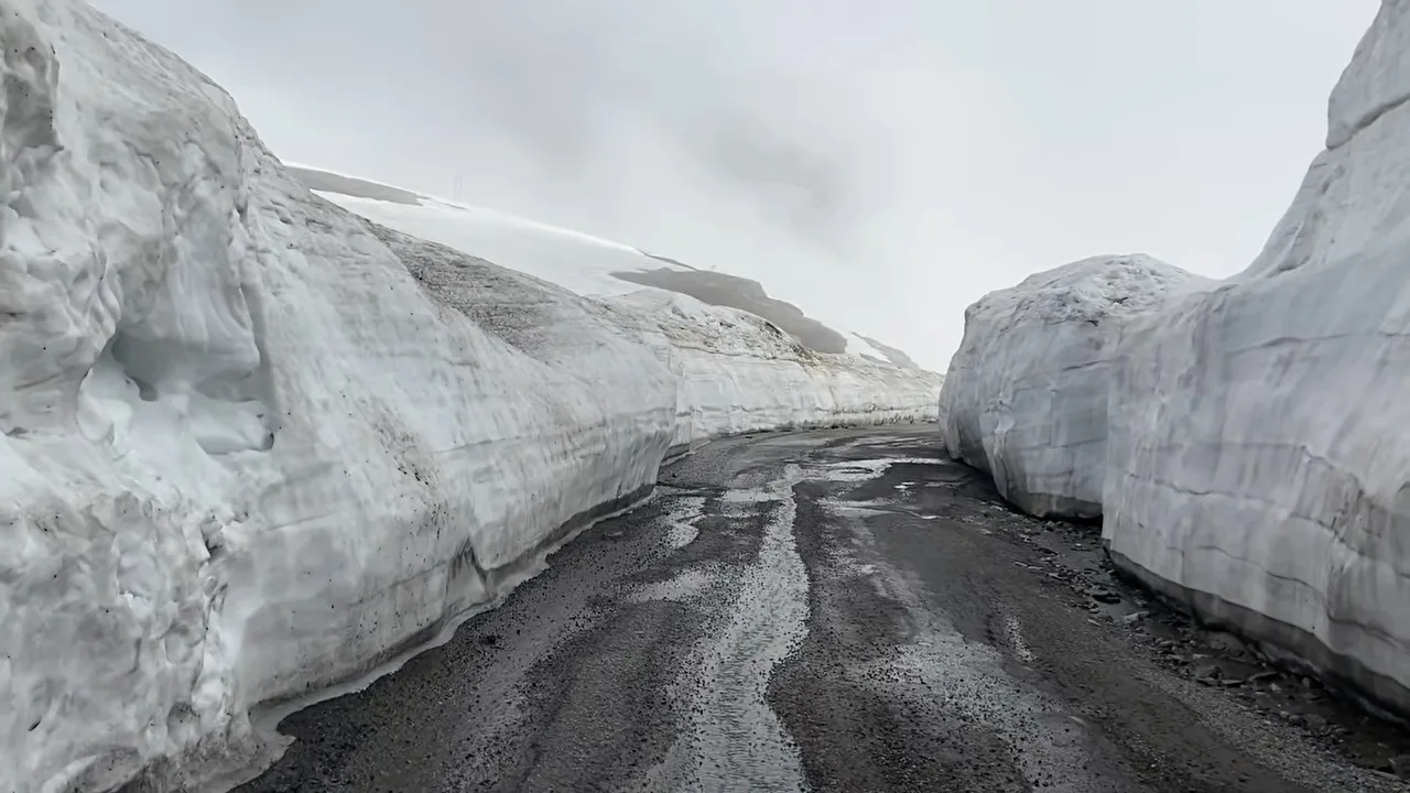Road cut through tall snow walls on the high route above Manali