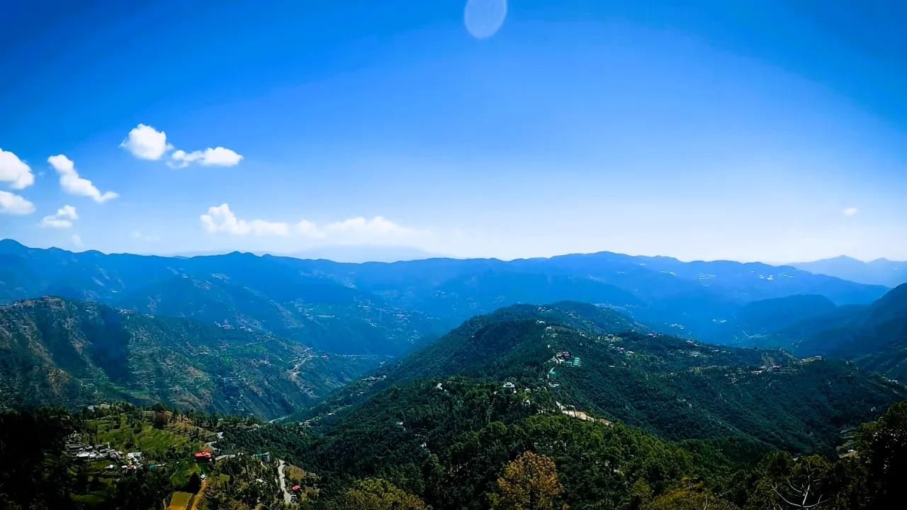Green forested hills around Shimla under a clear blue sky