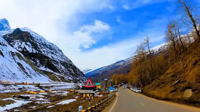 Mountain road through a valley below snowy peaks on the way to Manali