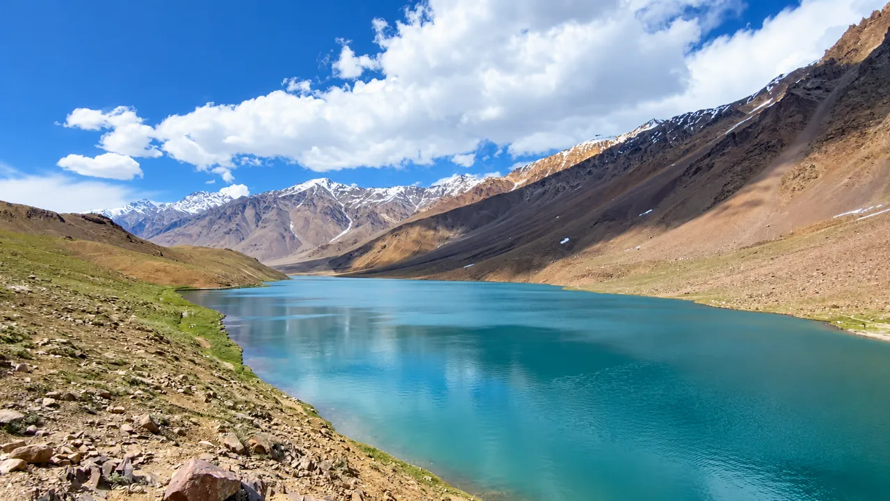 Turquoise Chandratal Lake between brown mountains and snowy peaks in Spiti