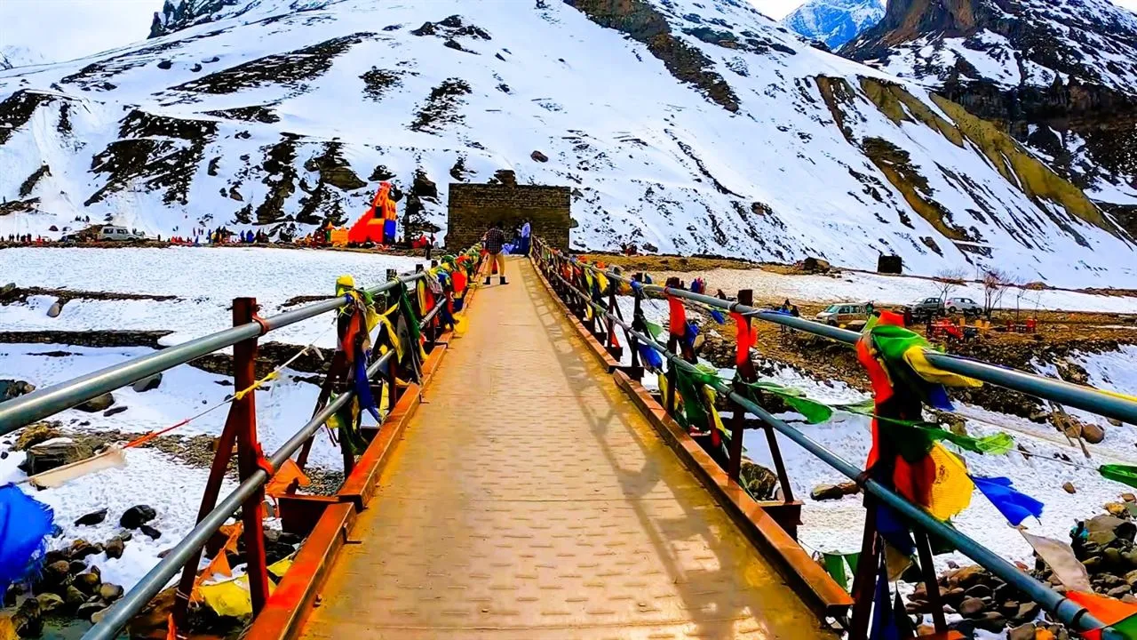 Prayer-flag bridge over a snowy valley near Manali